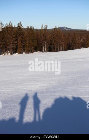 Schatten von zwei Menschen stehen auf einem Hügel in Lappland Landschaft im Winter. Stockfoto