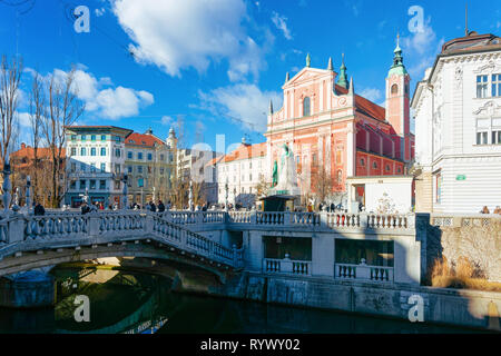 Ljubljana, Slowenien - 14. Januar 2019: Leute an der Franziskanerkirche und Triple Brücke über Fluss Ljubljanica Straßen der Altstadt in Ljubljana, Slowenien. Türme der Kathedrale und der wunderschönen slowenischen Stadt Stockfoto