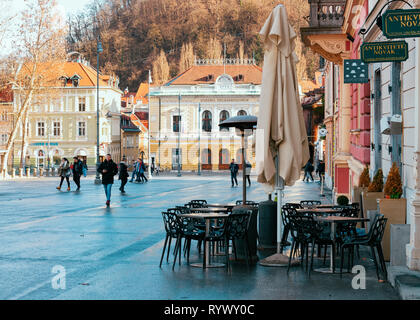 Ljubljana, Slowenien - 14. Januar 2019: Cafe auf Congress Square und das Stadtbild Ljubljanas Altstadt Straße, Slowenien in Abend. Restaurant mit Tischen und Stühlen in der wunderschönen slowenischen Stadtblick Stockfoto