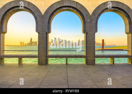 Moderne Wolkenkratzer von Doha West Bay Skyline bei Sonnenuntergang Licht durch Bögen der Museum entlang der Corniche in der katarischen Hauptstadt entfernt. Doha in Katar. Mitte Stockfoto