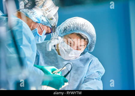 Porträt eines Chirurgen. Chirurgen arbeiten nach dem Patienten. Angespannt, ernsten Gesichter. Den realen Betrieb. Gespannte Atmosphäre im Operationssaal. Stockfoto