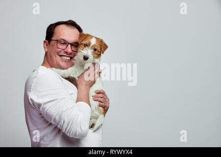 Der Hund liegt auf der Schulter seines Besitzers. Jack Russell Terrier in den Händen seiner Besitzer auf weißem Hintergrund. Das Konzept von Menschen und Tieren. T Stockfoto