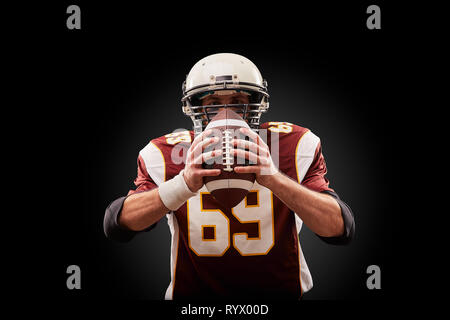 Portrait von American Football Spieler mit einem Ball mit beiden Händen Stockfoto