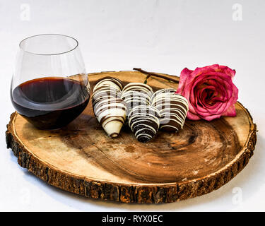 Mit Schokolade überzogene Erdbeeren auf Holz neben eine rosa Rose- und Rotwein Stockfoto