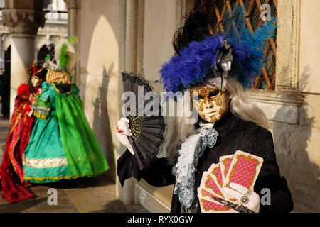 Frauen gekleidet in traditionelle Masken und Kostüme für Karneval in Venedig unter arch am Dogenpalast, Markusplatz, Venedig, Venetien, Italien Stockfoto