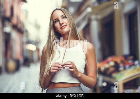Schöne junge blonde Frau im städtischen Hintergrund. Stockfoto