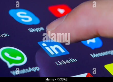 Finger drücken der Linkedin App Symbol auf einem Tablet-PC oder Handy Touchscreen. LinkedIn Verknüpfung. Stockfoto