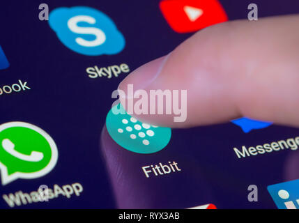 Finger drücken der Fitbit App Symbol auf einem Tablet-PC oder Handy Touchscreen. Fitbit Verknüpfung. Stockfoto