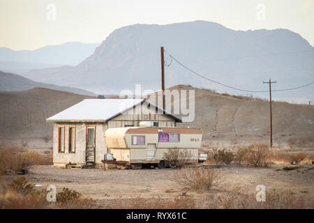 Landschaft mit Caravan RV und kleines Haus in der texanischen Wüste mit elektrischen Leitungen Stockfoto