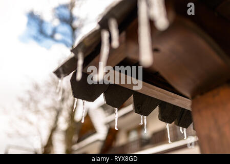 Hängenden Eiszapfen vom Dach eines hölzernen Gebäude auf einem Winter frostigen Tag, viel Schnee auf dem Dach. Stockfoto