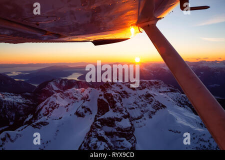 Blick von der kleinen Flugzeug über die wunderschöne Kanadische Berglandschaft fliegen während der pulsierende Sonnenuntergang. Nördlich von Vancouver, British Columbia, Stockfoto