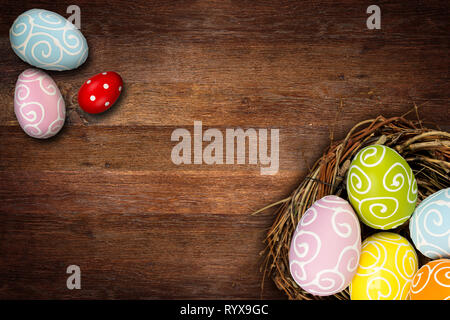 Bunte frohe Ostern Eier im Nest und Tulpen auf dunklen leeren urigen alten Eiche Holz Hintergrund mit copy Space Design Pattern. Stockfoto