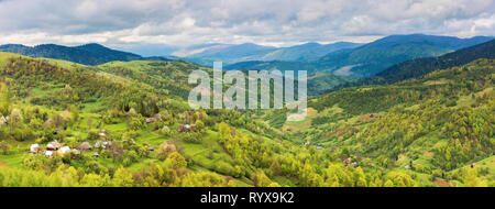 Panorama der bergigen Landschaft im Frühling. Dorf auf dem Hügel, Berge in der Ferne. trübes Wetter. Blick vom Hügel. Stockfoto