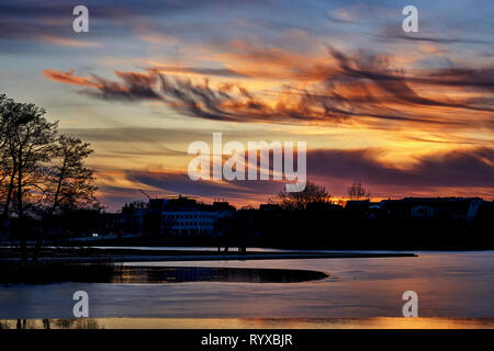 Eisige See mit Sonnenuntergang und die Stadt im Hintergrund. Mecklenburg-Vorpommern, Deutschland Stockfoto