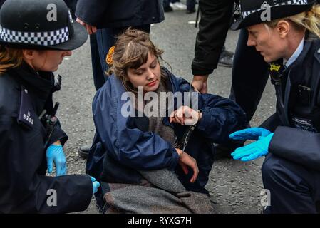 London, Großbritannien. 15 Mär, 2019. Ein Student ist auf die Westminster Bridge nach sich hinzusetzen Protest von Studenten Klimawandel Aktivisten verhaftet. Schülerinnen und Schüler gehen in den Streik in Großbritannien heute fordert mehr Maßnahmen gegen den Klimawandel. Polizisten fordern Sie hier mehrmals, wenn Sie sich hinstellen und ohne fremde Hilfe gehen, Sie dos nicht. Credit: Claire Doherty/Alamy leben Nachrichten Stockfoto