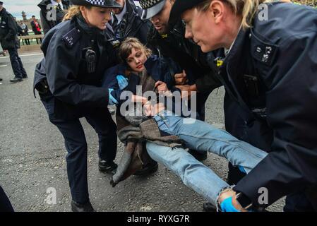 London, Großbritannien. 15 Mär, 2019. Ein Student ist auf die Westminster Bridge nach sich hinzusetzen Protest von Studenten Klimawandel Aktivisten verhaftet. Schülerinnen und Schüler gehen in den Streik in Großbritannien heute fordert mehr Maßnahmen gegen den Klimawandel. Polizisten fordern Sie hier mehrmals, wenn Sie sich hinstellen und ohne fremde Hilfe gehen, Sie dos nicht. Die Offiziere tragen Sie in Richtung zu einem Polizeiwagen. Credit: Claire Doherty/Alamy leben Nachrichten Stockfoto