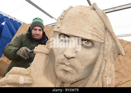 Binz, Deutschland. 12 Mär, 2019. Der Bildhauer Bagrat Stepanayan aus Russland arbeitet auf dem Sand Skulptur Johnny Depp als Captain Jack Sparrow in einer Szene des Films "Fluch der Karibik" auf dem Gelände der Sandskulpturenfestival. Künstlerinnen und Künstler aus verschiedenen europäischen Ländern werden derzeit erstellen 45 riesige Zahlen für die 10 Sand Skulptur zeigen im Ostseebad Binz. Der Sand Skulpturen zeigen, eröffnet am 16.03.2018. Quelle: Stefan Sauer/dpa-Zentralbild/dpa/Alamy leben Nachrichten Stockfoto