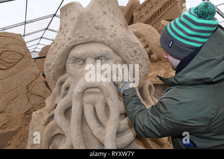 Binz, Deutschland. 12 Mär, 2019. Der Bildhauer Bagrat Stepanayan aus Russland arbeitet auf dem Sand Skulptur Captain Barbossa in einer Szene des Films "Fluch der Karibik" mit dem Film Davy Jones auf dem Gelände der Sandskulpturenfestival. Künstlerinnen und Künstler aus verschiedenen europäischen Ländern werden derzeit erstellen 45 riesige Zahlen für die 10 Sand Skulptur zeigen im Ostseebad Binz. Der Sand Skulpturen zeigen, eröffnet am 16.03.2018. Quelle: Stefan Sauer/dpa-Zentralbild/dpa/Alamy leben Nachrichten Stockfoto