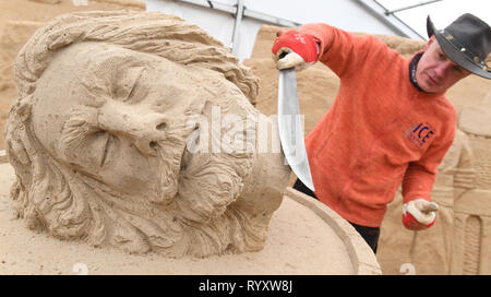 Binz, Deutschland. 12 Mär, 2019. Die litauischen Bildhauer Donatus Mockus arbeitet auf dem Sand Skulptur Klaus Störtebeker auf dem Gelände der Sandskulpturenfestival. Künstlerinnen und Künstler aus verschiedenen europäischen Ländern werden derzeit erstellen 45 riesige Zahlen für die 10 Sand Skulptur zeigen im Ostseebad Binz. Der Sand Skulpturen zeigen, eröffnet am 16.03.2018. Quelle: Stefan Sauer/dpa-Zentralbild/dpa/Alamy leben Nachrichten Stockfoto