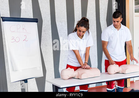 Hlw-Klassen mit Lehrern reden und demonstrieren, Erste Hilfe, Kompressionen und Reanimation. Hlw-Dummy auf dem Tisch. Stockfoto