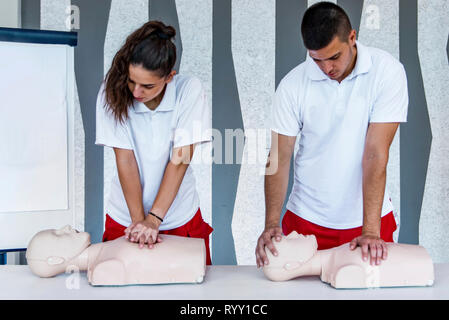 Hlw-Klassen mit Lehrern reden und demonstrieren, Erste Hilfe, Kompressionen und Reanimation. Hlw-Dummy auf dem Tisch. Stockfoto