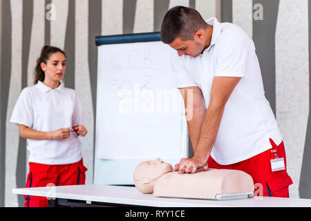 Hlw-Klassen mit Lehrern reden und demonstrieren, Erste Hilfe, Kompressionen und Reanimation. Hlw-Dummy auf dem Tisch. Stockfoto