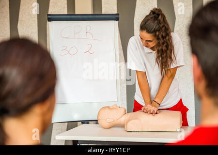 Hlw-Klassen mit Lehrern reden und demonstrieren, Erste Hilfe, Kompressionen und Reanimation. Hlw-Dummy auf dem Tisch. Stockfoto