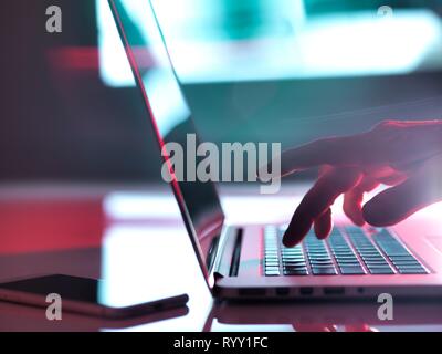 Mann der Texteingabe auf einem Laptop an seinem Schreibtisch. Stockfoto