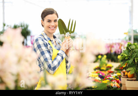 Lächelnde Frau im Garten der Blumen mit Garten Werkzeuge, Feder Konzept Stockfoto