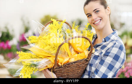 Lächelnde Frau mit Korb voller Mimosa Frühling Blumen, 8. März Frauentag Konzept Stockfoto