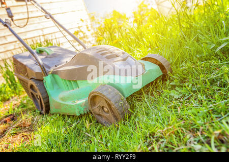 Rasenmäher schneiden grünen Gras im Hinterhof in sonniger Tag. Gartenbau Land lifestyle Hintergrund. Wunderschöne Aussicht auf frischen grünen Rasen im Sonnenlicht, Stockfoto