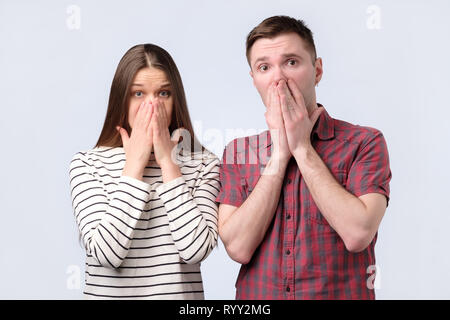 Schockiert Begeistert junge Paar für Mund mit den Händen an Kamera suchen Stockfoto