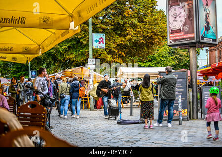 Touristen und Einheimische Deutsche genießen Sie einen Street Performer singen und Gitarre spielen Im Hackeschen Markt in Berlin Deutschland. Stockfoto