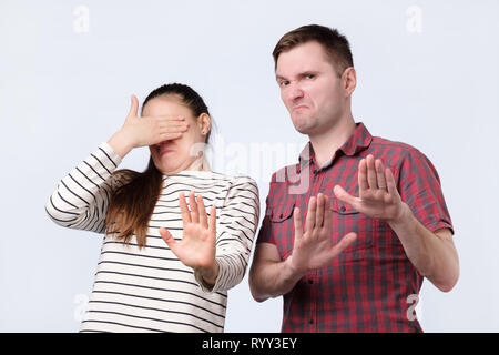 Portrait ofyoung Paar auf etwas Unangenehmes gestikulierte mit Händen, es nicht zu kaufen Stockfoto