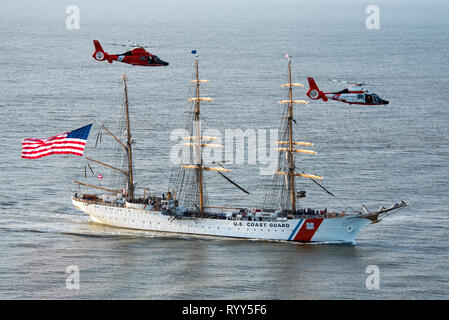 Coast Guard Cutter Eagle Transite auf der Savannah River in Richtung Savannah, Georgia, 15.03.2019, neben zwei Air Station Savannah Hubschrauber. Der Adler kam in der Savanne für St. Patrick's Day Wochenende mit über 100 Gästen an Bord. (U.S. Coast Guard Foto von Petty Officer 3. Klasse Ryan Dickinson) Stockfoto