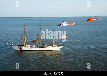 Coast Guard Cutter Eagle Transite auf der Savannah River in Richtung Savannah, Georgia, 15.03.2019, neben zwei Air Station Savannah Hubschrauber. Der Adler kam in der Savanne für St. Patrick's Day Wochenende mit über 100 Gästen an Bord. (U.S. Coast Guard Foto von Petty Officer 3. Klasse Ryan Dickinson) Stockfoto