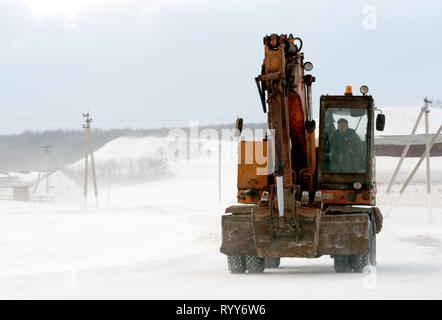 RAEVKA, Russland - Februar 22, 2019: Ein earthmover Kran bewegt sich entlang einer Straße im Schnee witner Raevka während der Monate. Diese Maschinen werden verwendet, um s zu löschen Stockfoto