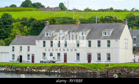 Die cushendun Gebäude in Nordirland ein weißes Gebäude mit dem Grünen Berg auf dem Hintergrund Stockfoto