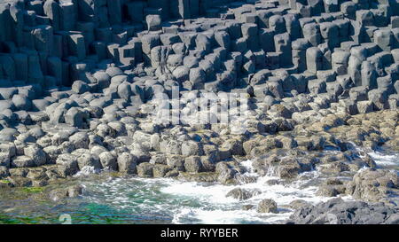 Die Felsen an der Küste in der Giants Causeway mit dem Spritzwasser der Wellen aus dem Meer Stockfoto