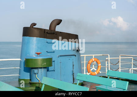 Rauch von der Fähre Rauchgas im Meer mit Sonne, Meer und blauem Himmel im Hintergrund, Thailand. An Bord einer Fähre, Schornstein oder Kreuzfahrtschiff, raucht Stockfoto