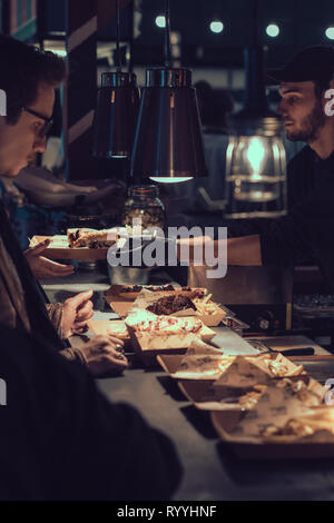 London, England - November 2018: Männer mit Take away Home Main Mahlzeiten auf der Street Food Markt Stockfoto