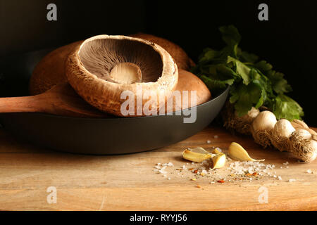 Frische rohe Portobello Pilze in der Pfanne auf hölzernen Tisch Stockfoto