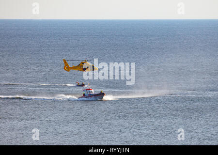 Ein Helikopter der Niederländischen coastgard ist Abseilen ein Mann über dem Meer während einer Rettung bohren Stockfoto