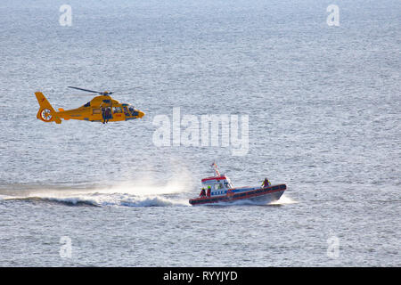 Ein Helikopter der Niederländischen coastgard ist Abseilen ein Mann über dem Meer während einer Rettung bohren Stockfoto