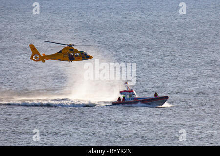 Ein Helikopter der Niederländischen coastgard ist Abseilen ein Mann über dem Meer während einer Rettung bohren Stockfoto