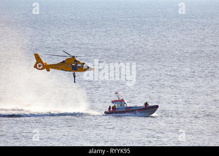 Ein Helikopter der Niederländischen coastgard ist Abseilen ein Mann über dem Meer während einer Rettung bohren Stockfoto