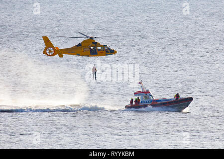 Ein Helikopter der Niederländischen coastgard ist Abseilen ein Mann über dem Meer während einer Rettung bohren Stockfoto