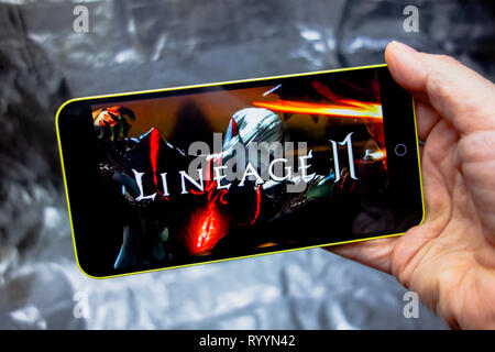Berdyansk, Ukraine - 16. März 2019: Hände, die ein Smartphone mit Lineage 2 revolution Spiel auf dem Anzeigebildschirm angezeigt. Stockfoto