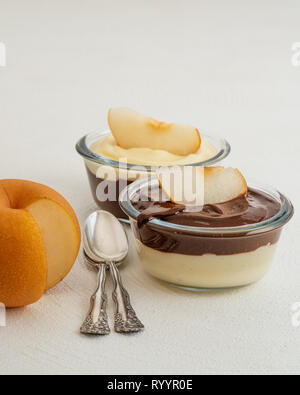 Schokolade und Vanille Pudding mit asiatischer Birne Schichten in einem Glas Schalen, Nahaufnahme auf Weiß. Köstliche, Glutenfreie Frühstück Stockfoto