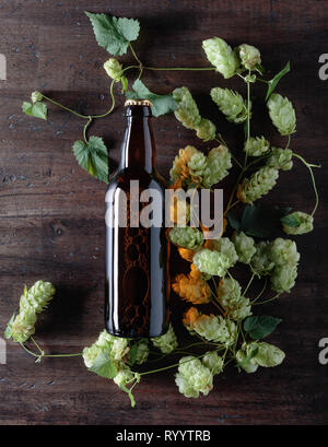Flasche Bier und Hopfen auf einem alten hölzernen Hintergrund. Ansicht von oben. Stockfoto